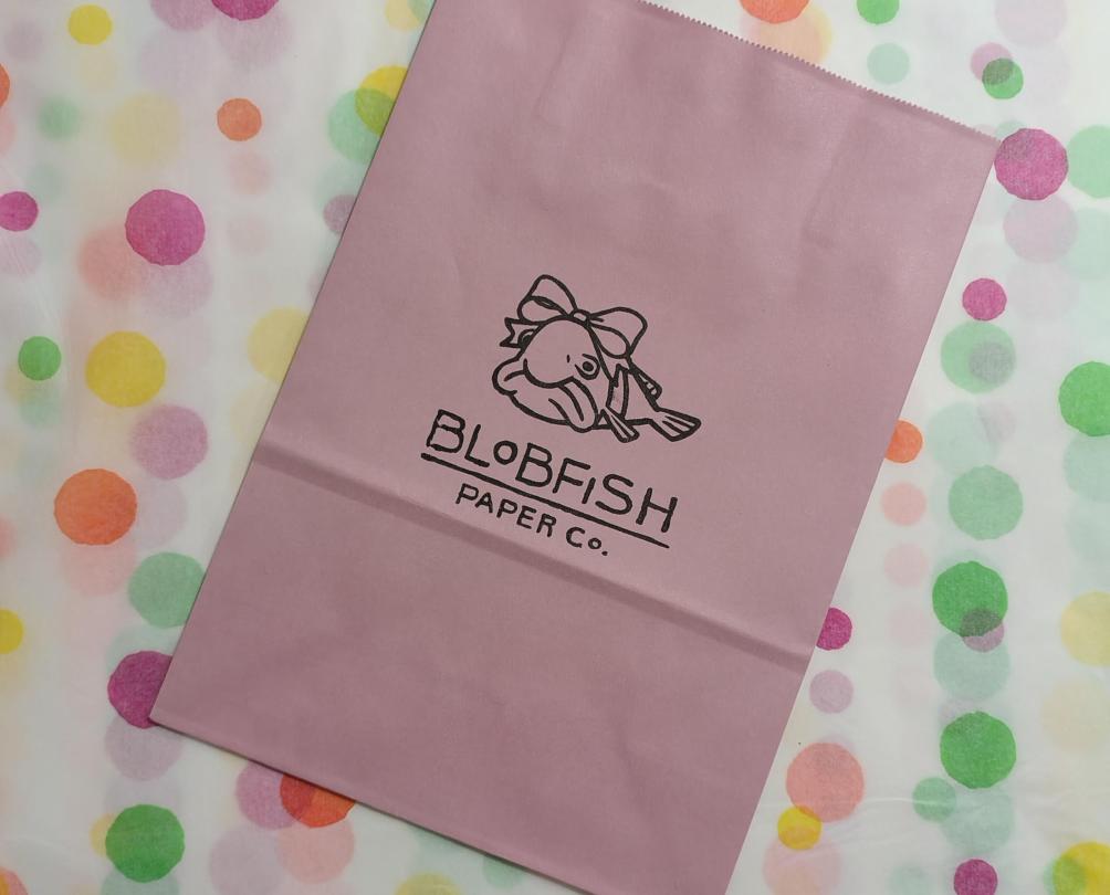 paper bag with logo on a colourful polka dot background 