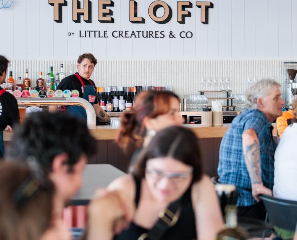 people sitting in a venue with a sign called The Loft in the background