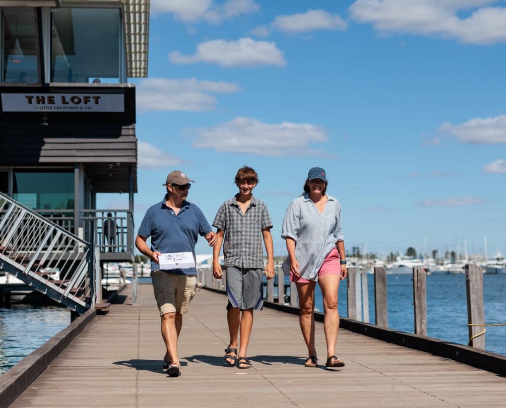 a family walking down the boardwalk in front a staircase and a sign saying THE LOFT