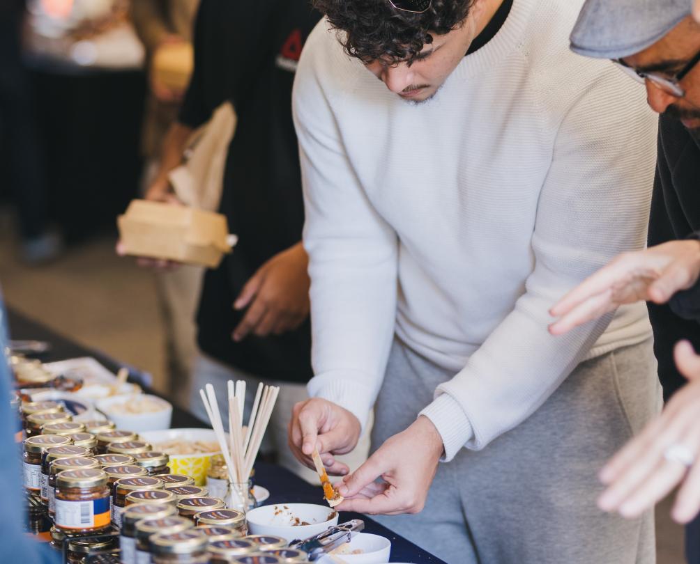 a group looking at tastings on a table and trying some with a little spoon 
