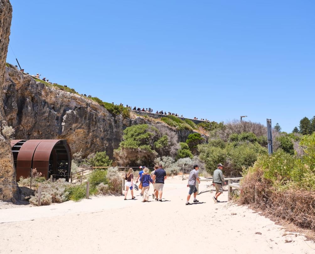 some people walking along the beach next to a tunnel 