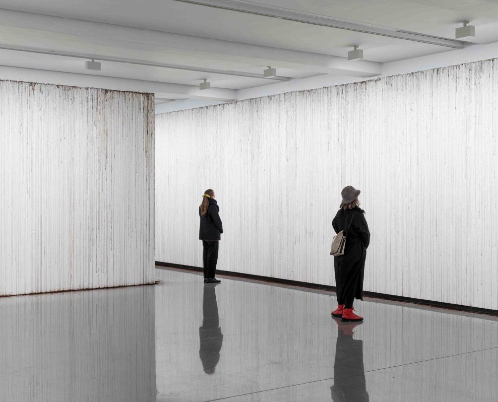 two people standing in a white room looking at the walls