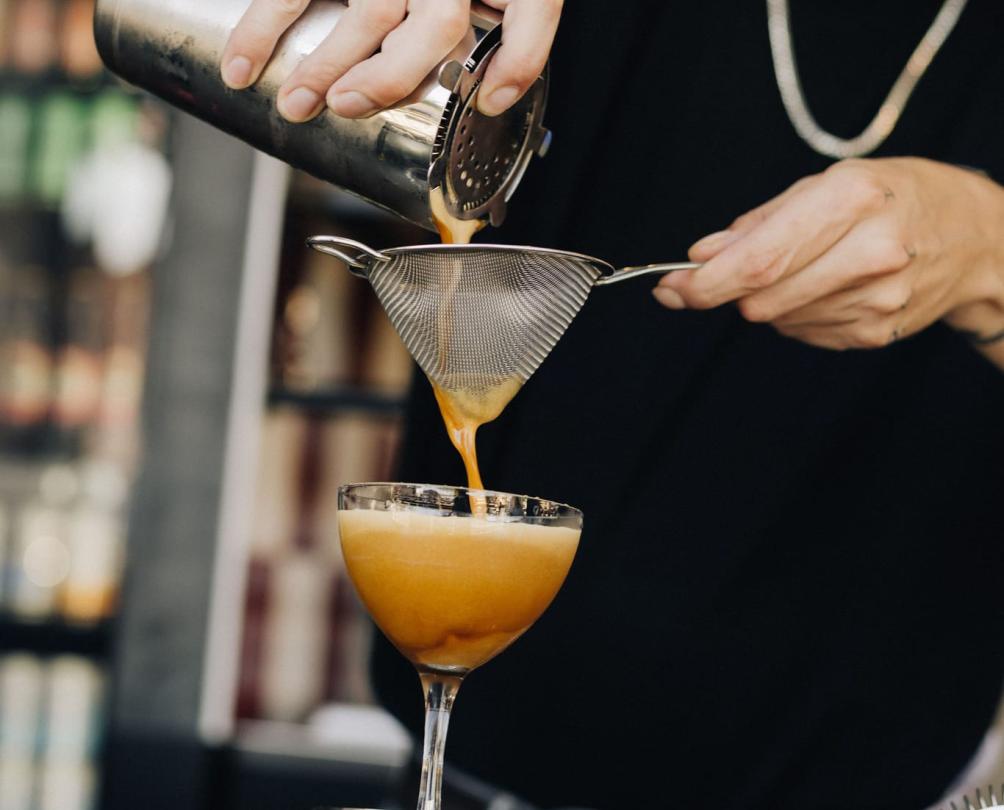 a bartender pouring out an espresso martini from a silver shaker