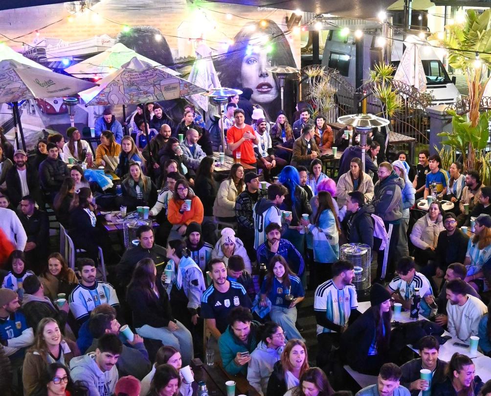 a crowd in a courtyard looking at a screen and cheering