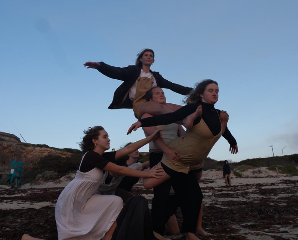 some people on the beach with arms outstretched holding each other up