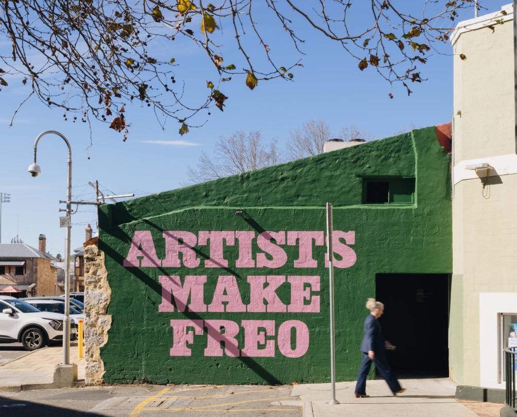 an arts mural on a wall in PIAZZA that says "artists make freo"