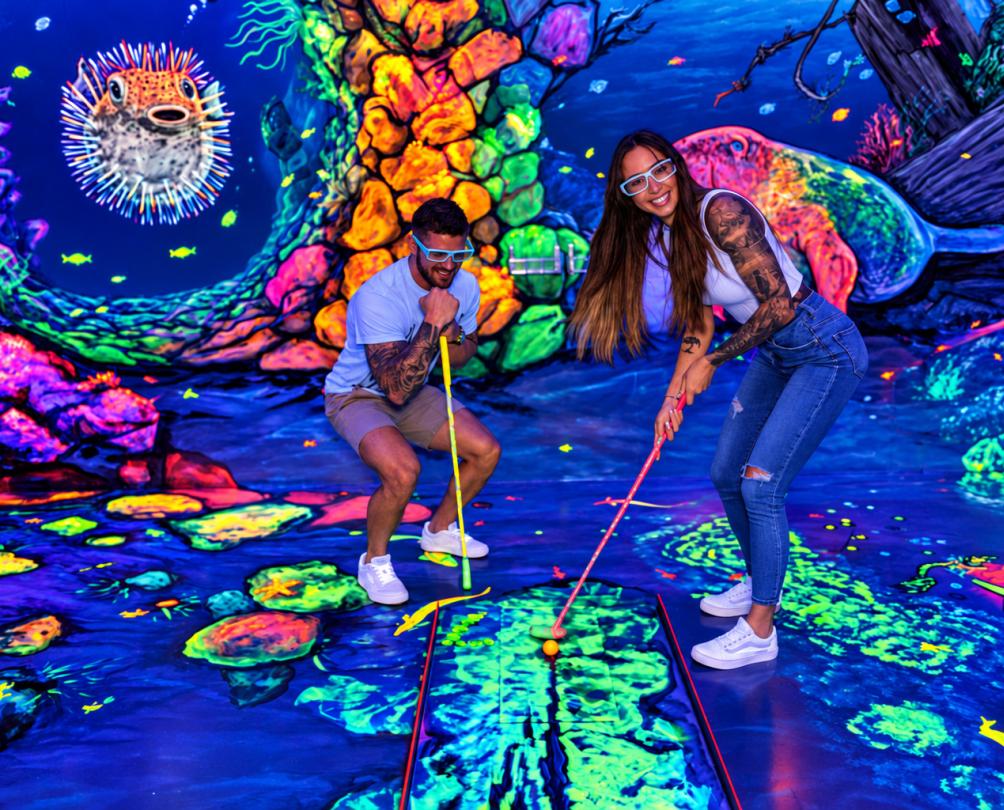 a couple on a date in a glow in the dark mini golf course
