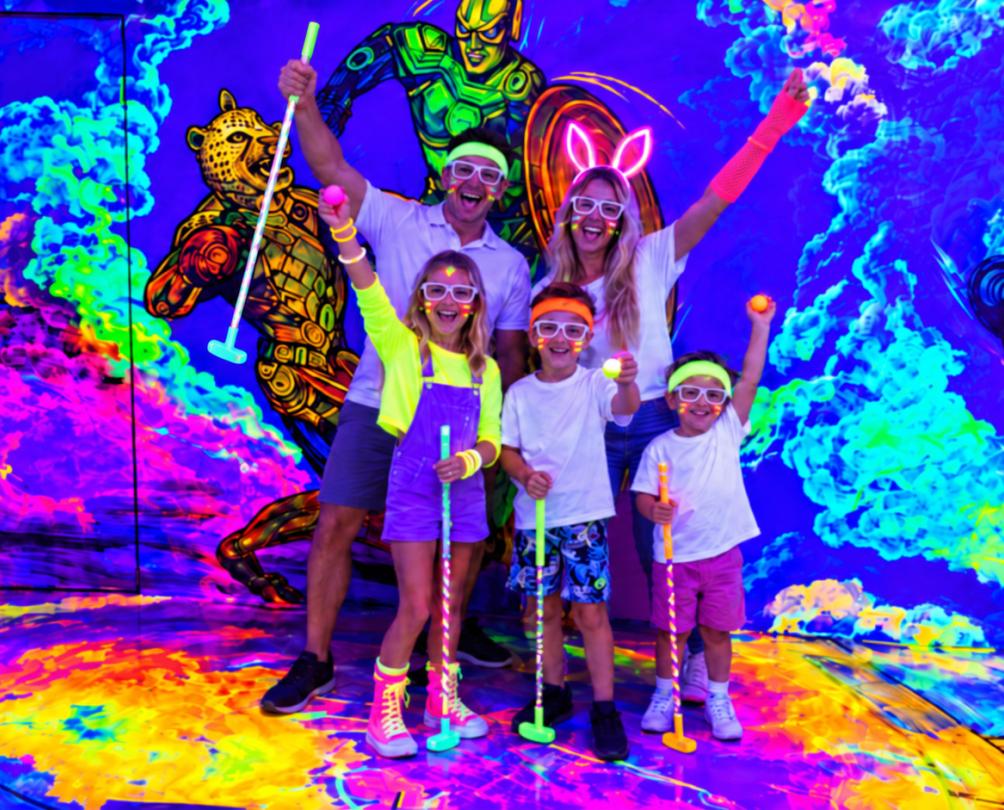 a family in a glow in the dark mini golf course