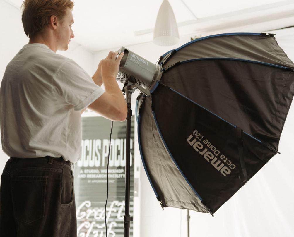 a man holding a black studio light in a white studio at Focuspocus in Fremantle