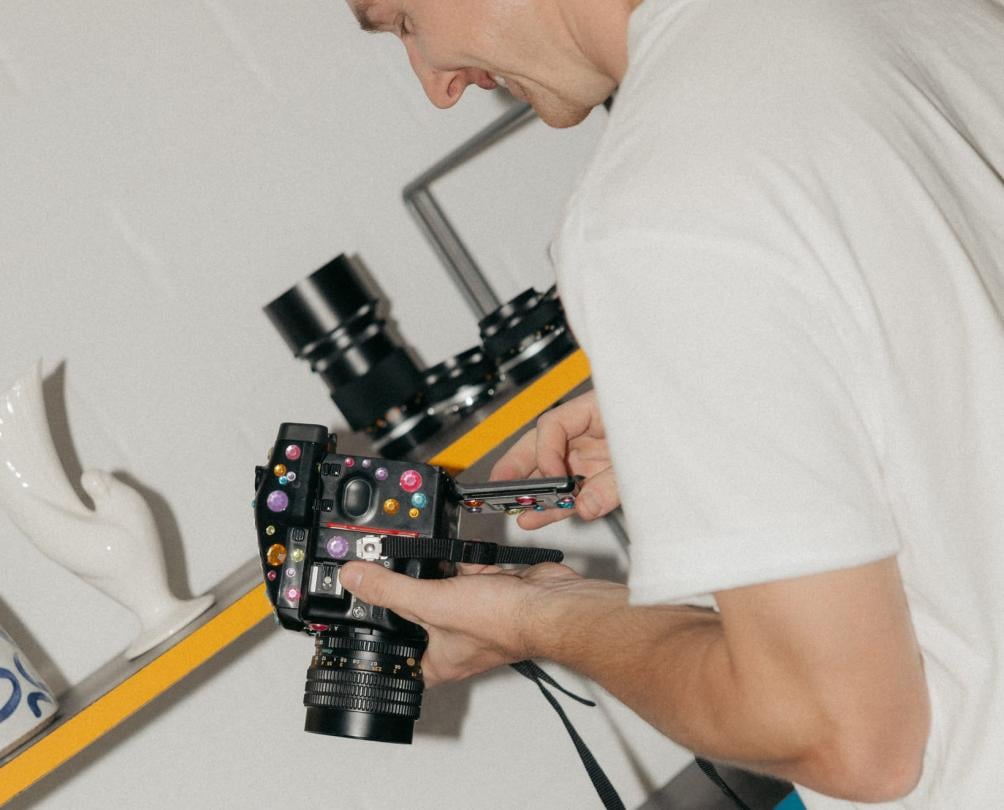 a man looking at an old camera in a white room 