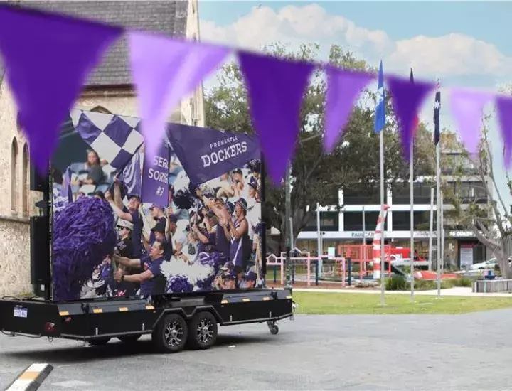 A big screen on wheels in the middle of a town square.