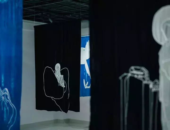 Black and blue artworks hanging from the ceiling in a small room