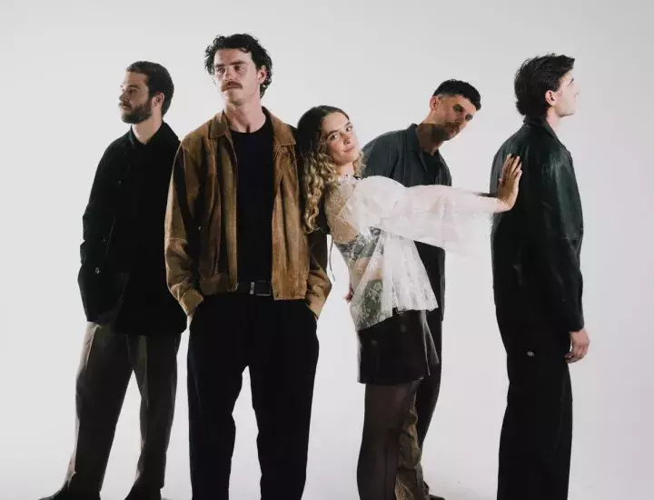 Four men and one woman post in front of a white backdrop.