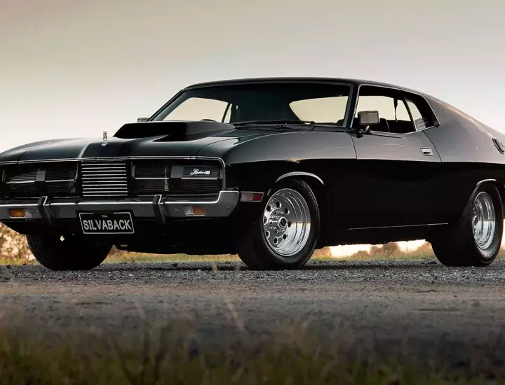 Black coupe car parked on a gravel road