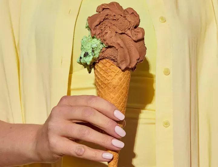 a hand holding a double scoop of ice cream 