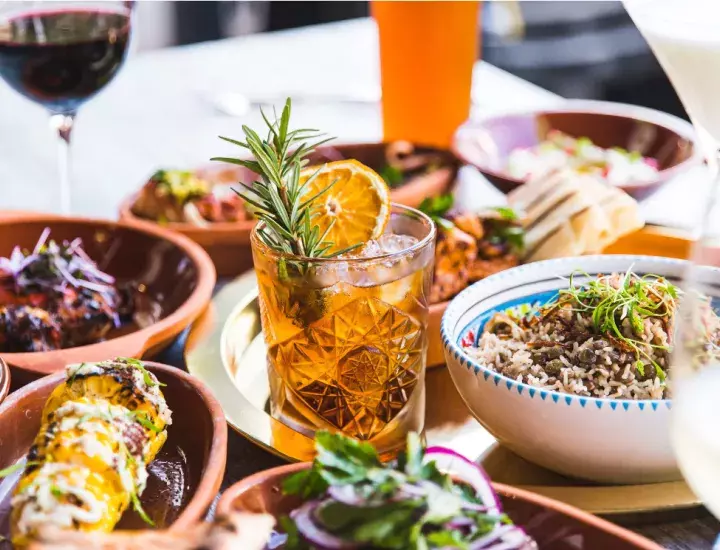 a table full of Middle Eastern food with a wine glass and a cocktail in the middle 