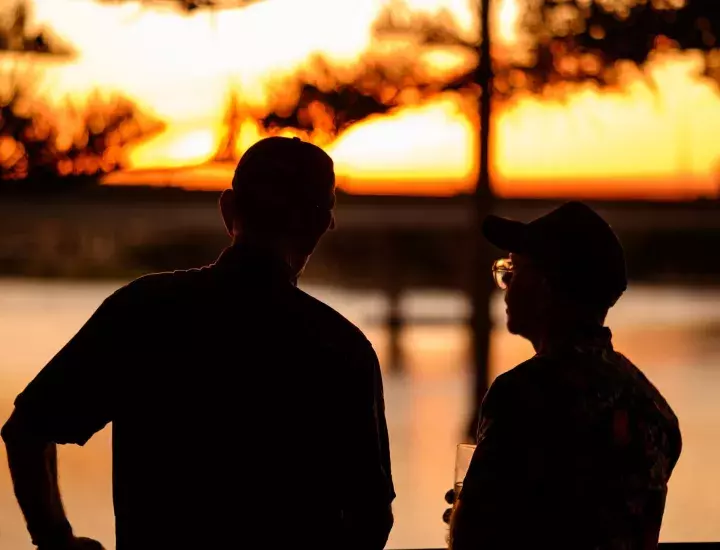 two men looking out at the river at sunset 
